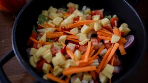 sliced carrots and green vegetable in black ceramic bowl